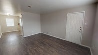 This single-floor, 1-bedroom, 1-bathroom unit offers a clean and functional layout with modern finishes throughout. The living areas are finished with rich, dark hardwood-style flooring that provides a warm and cohesive feel, complemented by neutral-toned walls and white baseboards that keep the space feeling bright and open. A closet with a paneled white door adds convenient storage to the main living area.

The kitchen is well-equipped with white cabinetry, light granite-style countertops, a stainless steel range with overhead ventilation, a stainless steel refrigerator, and a sink with ample counter space. A pantry area with built-in shelving provides additional storage.

The bedroom is carpeted for comfort, features a ceiling fan with a light fixture, and benefits from a window with blinds that allows natural light to filter in. A walk-in closet with built-in shelving adds generous storage capacity.

The bathroom is neatly appointed with a granite-style vanity top, a large mirror, white cabinetry, and a full tub-shower combination. Dark hardwood-style flooring carries through here as well, maintaining a consistent aesthetic. A window with blinds provides ventilation and natural light. Overall, the unit presents a tidy, move-in-ready environment with practical finishes throughout.