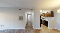 This single-floor residential unit offers a clean, neutral palette and a practical layout designed for comfortable everyday living. The main living area features warm hardwood-style flooring and a ceiling fan with lighting, while a wide window fitted with horizontal blinds allows natural light to fill the space. A dedicated dining area is highlighted by an elegant drum pendant light and matching hardwood-style flooring, creating a welcoming atmosphere for meals and gatherings.

The kitchen is well-equipped with rich, dark wood cabinetry, light granite-style countertops, a tiled backsplash, and black appliances including an electric range with an overhead exhaust hood. The kitchen flows naturally into the main living spaces via an open corridor.

A central hallway connects the living areas to the private bedrooms, each of which features plush carpeting, ceiling fans, and ample natural light through blinds-fitted windows. The bedrooms offer a quiet, restful environment with neutral wall tones.

The bathroom is neatly finished with hardwood-style flooring, a warm wood vanity with a white countertop, a mirrored medicine cabinet with bar lighting, and a full-size soaking tub with a built-in shower surround featuring integrated shelving. The space throughout is clean, functional, and move-in ready.