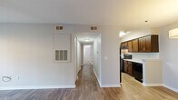 This single-floor residential unit offers a clean, neutral palette and a practical layout designed for comfortable everyday living. The main living area features warm hardwood-style flooring and a ceiling fan with lighting, while a wide window fitted with horizontal blinds allows natural light to fill the space. A dedicated dining area is highlighted by an elegant drum pendant light and matching hardwood-style flooring, creating a welcoming atmosphere for meals and gatherings.

The kitchen is well-equipped with rich, dark wood cabinetry, light granite-style countertops, a tiled backsplash, and black appliances including an electric range with an overhead exhaust hood. The kitchen flows naturally into the main living spaces via an open corridor.

A central hallway connects the living areas to the private bedrooms, each of which features plush carpeting, ceiling fans, and ample natural light through blinds-fitted windows. The bedrooms offer a quiet, restful environment with neutral wall tones.

The bathroom is neatly finished with hardwood-style flooring, a warm wood vanity with a white countertop, a mirrored medicine cabinet with bar lighting, and a full-size soaking tub with a built-in shower surround featuring integrated shelving. The space throughout is clean, functional, and move-in ready.