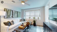 This single-floor residence offers a thoughtfully designed layout that balances comfort and modern style. The living room is a welcoming space anchored by a ceiling fan, wood-look flooring, and a large window dressed with horizontal blinds that invite abundant natural light. Botanical wall art and lush greenery add a fresh, organic touch to the room's contemporary aesthetic.

The kitchen is outfitted with crisp white shaker cabinetry, dark stone countertops, a subway tile backsplash, and a full suite of stainless steel appliances including a gas range, microwave, dishwasher, and refrigerator. Light wood-look flooring and recessed lighting complete the clean, functional space.

The primary bedroom is a serene retreat featuring plush carpet, a ceiling fan, and a large window with floor-length curtains that bathe the room in soft light. A walk-in closet provides generous storage, and a bold black-and-white art piece above the bed lends a sophisticated accent. The second bedroom is equally well-appointed with carpet, a large window, and direct access to a closet.

Two bathrooms serve the residence: one features a walk-in shower with a frameless glass door and a dual-sink vanity with dark stone countertops, while the second offers a full soaking tub and shower combination. Both bathrooms feature wood-look flooring and white cabinetry for a cohesive, polished look throughout.
