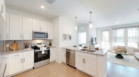 Located at 1700 Ranch Road in Nokomis, Florida, this one-bedroom, one-bathroom residence offers a thoughtfully designed single-floor layout filled with natural light and contemporary finishes. The open-concept living area seamlessly connects the kitchen, dining, and living spaces, creating an inviting and functional hub. The kitchen is well-appointed with white shaker cabinetry, granite countertops, stainless steel appliances including a range, microwave, dishwasher, and refrigerator, and a peninsula with bar seating illuminated by sleek pendant lighting. Light wood-style flooring flows throughout the main living areas, complementing the bright, neutral color palette. The living room features large windows that flood the space with natural light and provide outdoor views. The bedroom offers a comfortable retreat with plush carpet, dual windows, a ceiling fan, and direct access to a spacious walk-in closet with wire shelving. The bathroom includes a granite-topped vanity, a large mirror, and a separate walk-in closet entry. Additional highlights include a private balcony, a dedicated laundry area, and two closets for ample storage. The overall ambiance is clean, modern, and airy — ideal for comfortable Florida living.