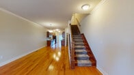 This three-story home offers a thoughtfully designed layout with distinct character across each level. The main floor makes an immediate impression with gleaming hardwood flooring that runs throughout the open living and dining areas, leading seamlessly into a well-equipped galley-style kitchen. The kitchen features rich warm-toned cabinetry lining both walls, granite countertops, stainless steel appliances including a range, dishwasher, microwave, and refrigerator, and the same hardwood flooring for continuity. Crown molding and a pendant light fixture add refined detail to the main living space, which is bathed in natural light. A staircase with carpet-lined treads and classic wood banisters connects the floors with a traditional, elegant touch. The upper level offers generously sized bedrooms with plush carpeting and vaulted ceilings that lend an airy feel, while windows provide pleasant outdoor views. Bedrooms include walk-in closets with built-in shelving for ample storage. The bathrooms are finished with large-format tile surrounds in the tub-shower combinations, marble-top vanities, and warm accent cabinetry. The lower level provides utility space with exposed infrastructure, suited for storage or mechanical systems. Overall, the home presents a clean, functional, and comfortable living environment with quality finishes throughout.