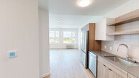 Located in Beaverton, Oregon, this apartment offers a well-planned one-bedroom, one-bathroom layout designed with modern aesthetics and functional efficiency in mind. Light wood-tone flooring flows consistently throughout the entire unit, creating a warm and cohesive atmosphere.

The kitchen is a standout feature, outfitted with a full suite of stainless steel appliances including a French door refrigerator, dishwasher, electric range, and over-the-range microwave. Cabinetry combines white uppers with warm wood-toned lowers, complemented by open floating shelves and a classic subway tile backsplash. A gray quartz countertop and undermount sink complete the sleek, contemporary look.

The bedroom is a bright, clean space with crisp white walls and a window offering views of the surrounding neighborhood and greenery, allowing for natural light. A dedicated closet provides practical storage.

The bathroom maintains the unit's modern design language, featuring a wood-toned vanity with a stone-finish countertop, recessed cabinetry hardware, and clean white walls that keep the space feeling fresh and uncluttered.

Overall, this apartment presents a cohesive, contemporary design with quality finishes throughout, making it an attractive and functional living space in Beaverton.