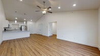 Located on SW Chickadee St in Bentonville, Arkansas, this single-story home presents a clean, modern aesthetic throughout its open-concept layout. The living area is anchored by soaring vaulted ceilings and a ceiling fan with a light fixture, creating an airy, spacious feel. Warm-toned wood-look flooring flows consistently throughout the entire home, lending visual continuity and a welcoming atmosphere.

The kitchen is a functional highlight, featuring white shaker-style cabinetry, granite countertops, a peninsula with pendant lighting overhead, and stainless steel appliances including a refrigerator, range, and microwave. This space opens directly into the living area, reinforcing the home's open and connected design.

The bedrooms are generously sized, each equipped with ceiling fans, large windows that invite natural light, and access to closet space. A hallway connects the private areas of the home to the main living spaces. The bathrooms maintain the home's clean palette, offering white cabinetry with granite countertops and tub-shower combinations with bright, neutral surroundings. Crisp white walls and recessed lighting throughout contribute to the home's fresh, move-in-ready presentation.