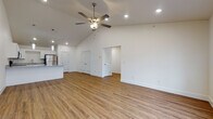 Located on SW Chickadee St in Bentonville, Arkansas, this single-story home presents a clean, modern aesthetic throughout its open-concept layout. The living area is anchored by soaring vaulted ceilings and a ceiling fan with a light fixture, creating an airy, spacious feel. Warm-toned wood-look flooring flows consistently throughout the entire home, lending visual continuity and a welcoming atmosphere.

The kitchen is a functional highlight, featuring white shaker-style cabinetry, granite countertops, a peninsula with pendant lighting overhead, and stainless steel appliances including a refrigerator, range, and microwave. This space opens directly into the living area, reinforcing the home's open and connected design.

The bedrooms are generously sized, each equipped with ceiling fans, large windows that invite natural light, and access to closet space. A hallway connects the private areas of the home to the main living spaces. The bathrooms maintain the home's clean palette, offering white cabinetry with granite countertops and tub-shower combinations with bright, neutral surroundings. Crisp white walls and recessed lighting throughout contribute to the home's fresh, move-in-ready presentation.