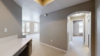 Located in Round Rock, Texas, this two-story home offers five bedrooms and thoughtfully designed living spaces spread across two floors. The main level is anchored by an open-concept kitchen and living room combination, where dark wood-tone cabinetry, stainless steel appliances, a built-in wine rack, and wood-look flooring give the kitchen a contemporary, functional feel. The adjoining living room is bright and welcoming, featuring crown molding, a ceiling fan, a tiled fireplace with a white mantle, and multiple windows that fill the space with natural light. A separate dining area benefits from a bay window configuration, flooding the room with views of surrounding greenery. Throughout the home, neutral-toned carpet and warm taupe walls create a cohesive, calming aesthetic. The bedrooms are generously sized, each with windows providing natural light and outdoor views. The primary bedroom includes a spacious walk-in closet fitted with multi-level wire shelving. The bathroom features a soaking tub with tiled surround and a combination shower. An attached garage with a concrete floor and direct interior access completes the home, offering practical convenience. Hallways and staircases connect all areas of the layout seamlessly, making this a well-organized and functional residence.