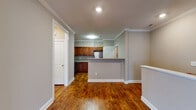 This single-floor residence offers a cohesive and functional layout finished with warm, neutral tones throughout. Rich hardwood flooring extends across the main living and kitchen areas, complemented by crisp white crown molding and baseboards that add a polished architectural detail to each room.

The kitchen is well-equipped and practical, featuring rich wood cabinetry, light countertops, and a full suite of stainless steel appliances including a range with over-the-range microwave and a refrigerator. A peninsula with a breakfast bar separates the kitchen from the adjacent living area, creating an open and connected flow between spaces.

The main living area is generously sized, bathed in natural light from multiple windows fitted with white plantation-style blinds. A ceiling fan provides both comfort and character. A built-in wood desk area offers a convenient workspace nook, adding a functional built-in element to the home.

The bedroom is carpeted for comfort and also features a ceiling fan and a window that allows natural light to fill the room. The full bathroom includes a wood-toned vanity with a wide mirror, a bright vanity light fixture, and a full tub and shower combination with white tile surround. The space as a whole presents a clean, move-in-ready environment with consistent finishes throughout.
