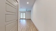 Located at 555 Promenade Pkwy in Irving, Texas, this single-floor unit offers a thoughtfully designed layout that maximizes its compact footprint. Light wood-style flooring runs continuously throughout the space, creating a cohesive and clean aesthetic that enhances the sense of openness.

The kitchen is a standout feature, boasting a central island with a dark granite countertop, undermount sink, and pendant lighting overhead. Medium-toned wood cabinetry lines the walls alongside a full suite of stainless steel appliances, including a refrigerator, range, microwave, and dishwasher. A tiled backsplash adds texture and visual interest. The kitchen flows seamlessly into the dining area, which benefits from notably tall ceilings that amplify the sense of volume.

The main living area is bright and open, illuminated by recessed lighting and a ceiling fan. French doors with slatted blinds allow natural light to filter in while providing access to the outdoors. The clean white walls and minimalist design contribute to an airy, modern ambiance throughout.

The bathroom features a wide wood-grain vanity with a quartz countertop, undermount sink, brushed nickel fixtures, and a framed mirror, delivering a polished, contemporary finish consistent with the rest of the unit.