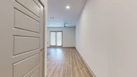 Located at 555 Promenade Pkwy in Irving, Texas, this single-floor unit offers a thoughtfully designed layout that maximizes its compact footprint. Light wood-style flooring runs continuously throughout the space, creating a cohesive and clean aesthetic that enhances the sense of openness.

The kitchen is a standout feature, boasting a central island with a dark granite countertop, undermount sink, and pendant lighting overhead. Medium-toned wood cabinetry lines the walls alongside a full suite of stainless steel appliances, including a refrigerator, range, microwave, and dishwasher. A tiled backsplash adds texture and visual interest. The kitchen flows seamlessly into the dining area, which benefits from notably tall ceilings that amplify the sense of volume.

The main living area is bright and open, illuminated by recessed lighting and a ceiling fan. French doors with slatted blinds allow natural light to filter in while providing access to the outdoors. The clean white walls and minimalist design contribute to an airy, modern ambiance throughout.

The bathroom features a wide wood-grain vanity with a quartz countertop, undermount sink, brushed nickel fixtures, and a framed mirror, delivering a polished, contemporary finish consistent with the rest of the unit.
