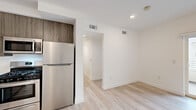 Located at 3057 W Pico Blvd. in Los Angeles, CA, this modern 2-bedroom, 1-bathroom unit offers a thoughtfully designed layout across a single floor. The contemporary kitchen is a standout feature, showcasing wood-grain cabinetry, bright white countertops, and a full suite of stainless steel appliances including a gas range, built-in microwave, dishwasher, and refrigerator — all complemented by light hardwood-style flooring that runs throughout the unit.

The entry hallway provides a clean transition into the living space, with the kitchen positioned conveniently just off the entrance. Both bedrooms are bright and minimalist, featuring white walls, light flooring, and windows with vertical blinds that allow natural light to filter in. The primary bedroom includes mirrored sliding closet doors, adding a sense of depth and functionality to the space. The secondary bedroom is cozy and well-proportioned, also benefiting from natural light.

The bathroom is finished in a clean, all-white palette with a combination tub and shower, light-toned flooring, and wood-accented cabinetry, maintaining the unit's cohesive modern aesthetic. Throughout the unit, the consistent use of neutral tones, light wood flooring, and contemporary finishes create a bright, airy, and move-in-ready living environment.
