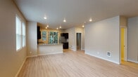 Located in the Cedar Mill neighborhood of Portland, Oregon, this single-floor residence offers a well-designed open-concept layout with a clean, contemporary aesthetic throughout. Light wood-style flooring flows seamlessly across the expansive living and dining area, enhanced by recessed lighting and neutral warm-toned walls that create a bright and welcoming ambiance. Multiple windows along the living area allow generous natural light to fill the space, offering views of the surrounding neighborhood.

The kitchen is outfitted with dark espresso cabinetry, granite countertops, and a full suite of stainless steel appliances, including a range, microwave, and refrigerator. A peninsula counter provides additional prep space and serves as a natural divider between the kitchen and living area. A sliding glass door from the kitchen opens directly onto a private balcony surrounded by mature evergreen trees, offering a peaceful outdoor retreat.

The bathroom features a dark-cabineted vanity with dual sinks and granite countertops, a large wall mirror, and a full shower-tub combination. A dedicated walk-in closet includes built-in wire shelving and hanging rods, providing ample organized storage. A second walk-in closet offers additional storage capacity. The overall design balances practicality with modern finishes throughout.