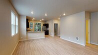 Located in the Cedar Mill neighborhood of Portland, Oregon, this single-floor residence offers a well-designed open-concept layout with a clean, contemporary aesthetic throughout. Light wood-style flooring flows seamlessly across the expansive living and dining area, enhanced by recessed lighting and neutral warm-toned walls that create a bright and welcoming ambiance. Multiple windows along the living area allow generous natural light to fill the space, offering views of the surrounding neighborhood.

The kitchen is outfitted with dark espresso cabinetry, granite countertops, and a full suite of stainless steel appliances, including a range, microwave, and refrigerator. A peninsula counter provides additional prep space and serves as a natural divider between the kitchen and living area. A sliding glass door from the kitchen opens directly onto a private balcony surrounded by mature evergreen trees, offering a peaceful outdoor retreat.

The bathroom features a dark-cabineted vanity with dual sinks and granite countertops, a large wall mirror, and a full shower-tub combination. A dedicated walk-in closet includes built-in wire shelving and hanging rods, providing ample organized storage. A second walk-in closet offers additional storage capacity. The overall design balances practicality with modern finishes throughout.