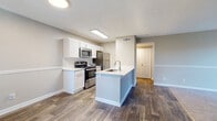 Located at 839 Shadow Elm Dr in Charlotte, NC, this single-floor residence offers a well-designed layout with a cohesive blend of modern finishes and comfortable living spaces throughout.

The kitchen is a standout feature, outfitted with white shaker cabinetry, white quartz countertops, a classic subway tile backsplash, and a full suite of stainless steel appliances including a gas range, microwave, and refrigerator. A peninsula island with a built-in sink provides additional prep space and opens directly to the main living area, which is finished with rich wood-look vinyl plank flooring.

The living room is generously sized, anchored by a corner brick fireplace and framed by a large sliding glass door that brings in natural light and provides outdoor access. The transition from hard flooring to plush carpet marks the boundary between the living and bedroom areas.

The bedrooms are carpeted and well-lit by windows with outdoor views of surrounding greenery, offering a quiet and comfortable retreat. Two full bathrooms serve the unit, each featuring white vanity cabinetry with brushed nickel hardware, white quartz countertops, and a tub-shower combination. The bathrooms are finished with the same wood-look flooring found throughout the main living areas, tying the overall aesthetic together.