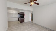 Located at 3431 Walnut Bend Ln in Houston, TX, this single-story unit offers a practical and well-organized layout with consistent light wood-style flooring running throughout the living spaces, creating a cohesive and clean aesthetic.

The living area is open and airy, featuring elevated ceilings and a ceiling fan that enhances airflow and comfort. Large windows allow natural light to filter in, brightening the neutral white walls. The space flows seamlessly toward the kitchen, which is defined by a half-wall peninsula and pendant lighting overhead.

The galley-style kitchen is well-appointed with rich dark espresso cabinetry, dark granite-style countertops, black appliances including an electric range, and a mosaic tile backsplash that adds a decorative accent. Ample upper and lower cabinet storage lines both sides of the kitchen, maximizing functionality.

The bedrooms continue the light flooring and neutral palette, each equipped with a ceiling fan and closet access. Natural light enters through slatted blinds, keeping the rooms bright and comfortable.

The bathroom features a full tub and shower combination with white tile surround, a dark vanity with granite-style countertop, and light wood-style flooring, maintaining the unit's consistent design language throughout.