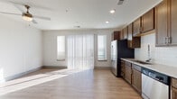 Located at 8320 University Executive Park Drive in Charlotte, NC, this single-floor unit offers a clean, modern design with a thoughtful layout. The open-concept living and kitchen area is bright and welcoming, with light wood-style flooring flowing throughout and large windows dressed with vertical blinds that allow generous natural light to fill the space. Ceiling fans add comfort to the living areas, enhancing the airy atmosphere.

The kitchen is well-appointed with rich, dark wood cabinetry, light stone-look countertops, a white subway tile backsplash, and a full suite of stainless steel appliances including a side-by-side refrigerator, electric range, over-the-range microwave, and dishwasher. A modern pull-down faucet completes the functional workspace.

A hallway connects the living area to the private rooms, featuring a sleek sliding barn-style door that adds a contemporary architectural detail. The corridor leads to additional rooms with carpet flooring, offering a contrast to the hard-surface common areas.

The bathroom is finished with large-format neutral tile on both the floor and tub surround, paired with polished chrome fixtures for a clean, cohesive look. Overall, the unit presents a well-maintained, move-in-ready space with modern finishes throughout.