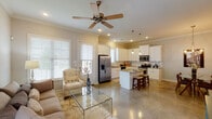 This single-story home offers three bedrooms and two bathrooms within a thoughtfully designed, open-concept floor plan. Crown molding details and polished concrete floors are consistent throughout, lending a cohesive and refined aesthetic across the living areas.

The kitchen serves as a central hub of the home, featuring crisp white shaker-style cabinetry, granite countertops, and a full suite of stainless steel appliances including a range, microwave, and dishwasher. A center island with bar seating provides additional prep space and casual dining options. Pendant lighting and recessed fixtures illuminate the space effectively.

The kitchen flows seamlessly into the living room, which is outfitted with a ceiling fan and large windows that allow natural light to fill the room. Adjacent to the kitchen, a dedicated dining area features a chandelier overhead and ample space for a full dining set.

A versatile additional room, currently configured as a home office, features neutral wall tones, a window with natural light, and crown molding. The bedrooms are comfortable and well-lit, each with windows and neutral finishes. The bathrooms include granite-topped vanities and white cabinetry, with one bathroom featuring a shower-tub combination.