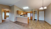Located at 924 Songbird Ln in Stevens Point, Wisconsin, this single-floor residence offers a well-organized layout designed for comfortable everyday living. The kitchen is a functional centerpiece, featuring warm honey-toned wood cabinetry extending to the ceiling for ample storage, a built-in range, white refrigerator, and a peninsula with a light-toned countertop that separates the kitchen from the adjacent dining and living areas. Stone-look tile flooring runs through the kitchen and dining space, transitioning to plush carpet in the living areas. The dining area benefits from vaulted ceilings and an elegant pendant chandelier, adding a sense of height and openness. The spacious living room is filled with natural light and features a sliding glass door leading to a private balcony with views of the surrounding landscape. The bedrooms are generously sized, carpeted for comfort, and equipped with baseboard heating and dedicated closets with built-in shelving. Windows throughout the bedrooms offer pleasant outdoor views. The full bathroom is finished with stone-look tile flooring, a rich wood vanity with a white countertop, and a full tub and shower surround. A coat closet near the entryway adds additional everyday convenience to this practical and inviting home.