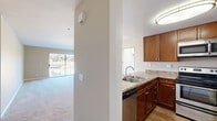This single-story residence offers a well-organized layout that balances functional living spaces with comfortable design details throughout. The kitchen is a standout feature, equipped with warm-toned wood cabinetry, granite-style countertops, and a full suite of stainless steel appliances including a range, microwave, refrigerator, and dishwasher. Wood-look flooring runs throughout the kitchen, adding warmth and durability to the space.

The living room is generously proportioned, featuring plush wall-to-wall carpeting, a ceiling fan, a fireplace with a tiled surround, and a sliding glass door that opens to a private balcony overlooking an outdoor view. Natural light flows freely into the space through large windows fitted with vertical blinds.

The bedrooms are carpeted and well-sized, with one room featuring mirrored sliding closet doors that enhance the sense of space and light. Each bedroom offers window access to natural light and is finished with neutral-toned walls.

Both bathrooms follow a consistent design language, each offering a single-sink vanity with granite-style countertops, wood cabinetry, a tub-shower combination, and light tile flooring, creating a clean and practical finish throughout.