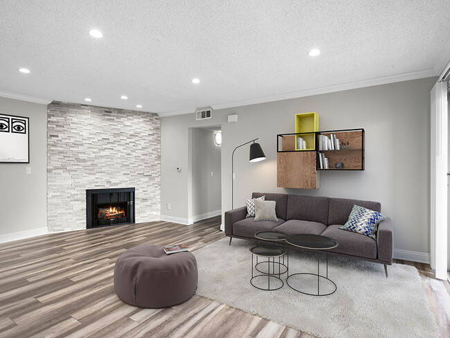 Living room with decorative stone wall, fireplace, and hardwood floors. - Hughes Regency