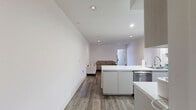 Located in the desirable West Los Angeles neighborhood, this 2-bedroom, 1-bathroom unit on Beloit Avenue offers a thoughtfully designed single-level layout. The open-concept kitchen and living area serves as the heart of the space, where a sleek peninsula with a white quartz countertop connects the kitchen to the main living zone. The kitchen is well-appointed with light grey cabinetry, a tile backsplash, and a full suite of stainless steel appliances including a gas range, microwave, refrigerator, and dishwasher. Hardwood-style flooring flows throughout the main living areas, complemented by recessed lighting that keeps the space bright and modern. The living area offers generous room for seating and relaxation. A hallway connects the main area to the two bedrooms, both of which feature plush carpeting and ample natural light. The primary bedroom includes a sliding glass door leading to an outdoor view, while the second bedroom features a built-in closet with shelving. The shared bathroom is finished with white tile flooring and a frameless glass-enclosed shower. Clean white walls and a neutral palette throughout create a cohesive, contemporary aesthetic suited to a range of lifestyles.