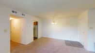 Located off I-40 E in Winston-Salem, NC, this single-floor residential unit offers a practical and comfortable layout designed for everyday living. The spacious living and dining area is finished with plush neutral carpet and features a textured ceiling, with a classic brass chandelier providing warm overhead lighting. The entry transitions seamlessly from a hard-surface foyer into the carpeted main living space, creating a clear sense of arrival. Adjacent to the living and dining area, the galley-style kitchen is efficiently arranged with warm wood-toned cabinetry lining both walls, offering generous storage. The kitchen is equipped with a coil-burner electric range, dishwasher, and full-size refrigerator, all set above durable wood-look vinyl flooring. The bedrooms are generously proportioned, each finished with soft neutral carpet and textured ceilings. Natural light enters through windows fitted with horizontal blinds, offering views of the surrounding greenery. Ceiling light fixtures and ample wall outlets are present throughout. The unit includes two full bathrooms, each featuring a tub-shower combo, toilet, and vanity with countertop. One bathroom showcases updated wood-look flooring and a bright mirror, while the other maintains a clean, functional design. Overall, the unit presents a tidy, move-in-ready interior with consistent neutral tones throughout.