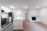 Located at 902 W Remington Dr in Sunnyvale, CA, this single-floor, one-bedroom, one-bathroom residence offers a clean, modern aesthetic throughout its thoughtfully designed layout. The open-concept living and dining area is anchored by a classic brick fireplace, creating a warm focal point, while recessed lighting and large windows allow natural light to fill the carpeted space. A ceiling fan adds comfort to the living area.

The kitchen is well-appointed with white shaker cabinetry, a white quartz peninsula, stainless steel appliances including a refrigerator, range, microwave, and dishwasher, and a skylight overhead that brightens the space. Light wood-look flooring runs through the kitchen and hallway, complementing the neutral palette throughout.

The bedroom is a comfortable, carpeted retreat with natural light from a window fitted with blinds, offering views of surrounding greenery. Three closets provide generous storage, including one with mirrored sliding doors. The bathroom features a full tub-shower combination with gold-toned fixtures and a privacy window. In-unit laundry adds everyday convenience, completing this efficiently designed Sunnyvale residence.