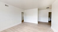Located at 1956 Marseille Dr in Miami Beach, FL, this single-floor 1-bedroom, 1-bathroom unit offers a clean, minimalist aesthetic defined by crisp white walls and light-toned wood laminate flooring that runs throughout the space. The open combined living and dining area serves as the heart of the unit, providing a versatile layout filled with natural light from large windows that frame views of the surrounding greenery. The space flows efficiently through a connecting hallway that links the main living area to the private quarters. The bedroom is a well-proportioned retreat featuring a mirrored sliding closet door, a second closet, and a window that brings in additional natural light. Altogether, three closets throughout the unit offer generous storage for a space of this size. The kitchen is functional and neatly appointed with white cabinetry, light countertops, a stainless steel sink, and a window that keeps the area feeling open and airy. The bathroom features a full tub-shower combination with white tile surround and a window for natural ventilation. Central air conditioning is present throughout, indicated by ceiling vents visible in multiple rooms. The overall ambiance is bright, clean, and move-in ready, well-suited for those seeking a low-maintenance Miami Beach residence.