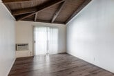 Located at 8100 Park Plaza in Stanton, California, this single-story home offers a thoughtfully designed layout with a mix of architectural character and practical living spaces. The standout feature of several rooms is the dramatic vaulted ceiling with exposed dark wood beams and a wood-planked ceiling surface, adding warmth and a distinct architectural charm. Light-toned luxury vinyl plank flooring runs throughout the main living areas and bedrooms, lending a clean, modern aesthetic.

The open-concept living and kitchen area is anchored by the vaulted beamed ceiling, transitioning seamlessly from a wood-floored living space to a tile-floored kitchen. The kitchen is equipped with light wood cabinetry, granite-style countertops, a double stainless steel sink, and a gas range. A peninsula counter provides additional workspace and separation between the kitchen and living zones.

The bedrooms are bright and airy, with large windows and sliding glass doors dressed in vertical blinds that invite natural light. Some bedrooms feature the vaulted beam ceilings, while others have a textured finish ceiling. The bathroom includes a wood-cabinet vanity with granite-style countertops, a large mirror, and a tiled tub-shower combination with tile flooring throughout. Vertical blinds and ample windows provide views of surrounding greenery.
