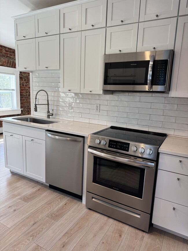 Kitchen has two walls of cabinetry including quartz countertops, large sink and upgraded appliances. - 427 Klotter Ave