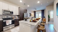 This thoughtfully designed single-floor residence offers a cohesive blend of modern style and everyday functionality. The kitchen is a standout feature, showcasing two-tone cabinetry with dark espresso lower cabinets and crisp white upper cabinets, granite countertops, a subway tile backsplash, and a full suite of stainless steel appliances. A large island with seating provides both additional prep space and a casual dining option. The kitchen flows seamlessly into the open living area, which is finished with wood-look plank flooring and receives generous natural light through glass doors that open to an outdoor balcony. A ceiling fan adds to the comfort of the space. The bedroom is a calm retreat, featuring plush carpet, multiple windows dressed with blinds and sheer curtains, and a ceiling fan overhead. The bathroom is generously proportioned, with dark cabinetry, dual granite-topped vanities, a large mirror, a tub and shower combination with marble-style tile surround, and wood-look flooring that ties the space together. Throughout the residence, a neutral color palette, recessed lighting, and consistent high-quality finishes create a polished and inviting atmosphere.