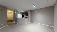This single-floor residence in Cary, NC offers a well-designed open layout with a neutral taupe color palette and white crown molding throughout the main living area. The living space is generously proportioned, featuring plush wall-to-wall carpeting, a ceiling fan, and windows that allow natural light to filter in with views of surrounding greenery.

The kitchen is a functional highlight, featuring rich dark wood cabinetry, granite-look countertops, a white subway tile backsplash, and stainless steel appliances including an electric range, microwave, and refrigerator. A breakfast bar peninsula connects the kitchen to the living area, enhancing the open-concept flow.

The bedrooms are carpeted and each includes a ceiling fan and a window with outdoor views. One bedroom benefits from a spacious walk-in closet outfitted with multi-tiered wire shelving for organized storage.

The bathrooms are well-appointed, with the primary bath featuring an extended dark wood double vanity with granite countertops, wall-mounted shelving, and wood-look flooring. A secondary bathroom includes a tiled tub-shower combination, wood-look flooring, and a window for natural ventilation.