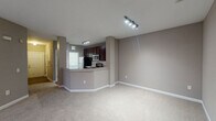 This single-floor residence in Cary, NC offers a well-designed open layout with a neutral taupe color palette and white crown molding throughout the main living area. The living space is generously proportioned, featuring plush wall-to-wall carpeting, a ceiling fan, and windows that allow natural light to filter in with views of surrounding greenery.

The kitchen is a functional highlight, featuring rich dark wood cabinetry, granite-look countertops, a white subway tile backsplash, and stainless steel appliances including an electric range, microwave, and refrigerator. A breakfast bar peninsula connects the kitchen to the living area, enhancing the open-concept flow.

The bedrooms are carpeted and each includes a ceiling fan and a window with outdoor views. One bedroom benefits from a spacious walk-in closet outfitted with multi-tiered wire shelving for organized storage.

The bathrooms are well-appointed, with the primary bath featuring an extended dark wood double vanity with granite countertops, wall-mounted shelving, and wood-look flooring. A secondary bathroom includes a tiled tub-shower combination, wood-look flooring, and a window for natural ventilation.