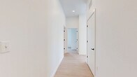 This well-designed 2-bedroom, 2-bathroom residence in Revere, MA offers a clean, modern aesthetic throughout its thoughtfully laid-out single floor. Light wood-tone flooring flows consistently across the living areas and bedrooms, complementing the crisp white walls and creating a bright, cohesive atmosphere.

The kitchen is a standout feature, appointed with sleek taupe cabinetry, white quartz countertops, a light gray subway tile backsplash, and stainless steel appliances including a range, microwave, refrigerator, and dishwasher. Matte black hardware and a black pull-down faucet add a contemporary contrast. A large kitchen island provides additional prep and dining space beneath modern pendant lighting.

The primary bedroom is a comfortable retreat featuring sliding glass doors that open to a private balcony, offering scenic views of the surrounding greenery. The second bedroom receives ample natural light through a tall window. Both rooms feature the same light wood flooring found throughout the unit.

The two bathrooms are finished with light tile flooring and warm wood-toned vanities. One bathroom features a full soaking tub with tiled surround, while the other is efficiently designed with clean, simple fixtures. White interior doors with matte black hardware tie the modern design together seamlessly.