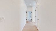 This well-designed 2-bedroom, 2-bathroom residence in Revere, MA offers a clean, modern aesthetic throughout its thoughtfully laid-out single floor. Light wood-tone flooring flows consistently across the living areas and bedrooms, complementing the crisp white walls and creating a bright, cohesive atmosphere.

The kitchen is a standout feature, appointed with sleek taupe cabinetry, white quartz countertops, a light gray subway tile backsplash, and stainless steel appliances including a range, microwave, refrigerator, and dishwasher. Matte black hardware and a black pull-down faucet add a contemporary contrast. A large kitchen island provides additional prep and dining space beneath modern pendant lighting.

The primary bedroom is a comfortable retreat featuring sliding glass doors that open to a private balcony, offering scenic views of the surrounding greenery. The second bedroom receives ample natural light through a tall window. Both rooms feature the same light wood flooring found throughout the unit.

The two bathrooms are finished with light tile flooring and warm wood-toned vanities. One bathroom features a full soaking tub with tiled surround, while the other is efficiently designed with clean, simple fixtures. White interior doors with matte black hardware tie the modern design together seamlessly.