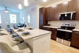 This contemporary 930 square foot apartment in Elizabethtown, KY offers a harmonious blend of style and functionality. The open-concept design seamlessly integrates the kitchen, living, and dining areas, creating a spacious feel. The kitchen boasts rich, dark wood cabinetry, granite countertops, and stainless steel appliances, including a large refrigerator and built-in microwave.

Both bedrooms feature plush carpeting, ceiling fans, and large windows that flood the spaces with natural light. The primary bedroom, measuring 150 square feet, provides ample space for relaxation. The bathrooms are well-appointed with granite vanity tops, modern fixtures, and a combination of tiled and wood-look flooring.

Throughout the apartment, wood-look flooring adds warmth and durability. The living area is accentuated by a stylish ceiling fan and includes a comfortable seating area perfect for entertainment. A sleek TV mount and contemporary media console offer modern convenience.

Additional features include in-unit laundry facilities and generous closet space with wire shelving systems. The apartment's neutral color palette and clean lines create a canvas for personal style, while the large windows offer views of the surrounding area, enhancing the overall living experience.