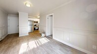 Located in Millcreek, Utah, this two-bedroom, one-bathroom unit offers a thoughtfully designed layout that maximizes every square foot of its compact footprint. The living room makes a strong first impression with elegant wainscoting panels lining the walls, crown molding, and light-toned luxury vinyl plank flooring that carries throughout the main living areas. Large sliding glass doors flood the space with natural light and provide direct access to a private balcony, offering outdoor views of the surrounding neighborhood. The open sightline from the living room into the kitchen creates a connected, functional flow. The kitchen is well-appointed with white shaker-style cabinetry, stainless steel appliances including a refrigerator, range, and over-the-range microwave, and light hardwood-style flooring that complements the cabinetry. Both bedrooms are carpeted for comfort, featuring neutral tones, baseboard heating, and dedicated closets. The spacious primary bedroom provides ample room for furnishings, while the second bedroom is a comfortable size with a window that welcomes natural light. The shared bathroom includes a vanity with a well-lit mirror. Throughout the unit, a neutral color palette and clean finishes create a bright, inviting atmosphere suited for everyday living.