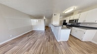 Located at 8401 Spain Rd NE in Albuquerque, New Mexico, this compact and efficiently designed one-bedroom, one-bathroom unit makes excellent use of its cozy footprint. Wood-look plank flooring flows consistently throughout the entire space, tying each room together with a warm, cohesive feel. Textured ceilings add a classic touch overhead.

The open-concept living and kitchen area forms the heart of the unit. The kitchen is well-appointed with white cabinetry, dark countertops, stainless steel appliances including a gas range, microwave, and refrigerator, and a peninsula that doubles as a breakfast bar. A pendant light and flush-mount ceiling fixture provide ample illumination, while a window allows natural light to brighten the dining area.

The living area offers a clean, open canvas with horizontal blind-covered windows that diffuse soft, natural light throughout the day. A baseboard heating unit ensures year-round comfort.

The spacious primary bedroom features neutral gray walls, a textured ceiling, additional baseboard heating, and a generous reach-in closet with bifold doors and a full-width hanging rod for ample storage.

The bathroom is clean and functional, featuring a dark-countertop vanity with white cabinetry, a full soaking tub with shower, and wood-look flooring that mirrors the rest of the unit.
