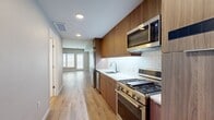 This 420 square foot apartment in Oakland, CA, offers a thoughtful blend of style and functionality. The single-floor layout maximizes space efficiency, featuring an open-plan design that seamlessly integrates the living room and kitchen areas. The living room boasts floor-to-ceiling windows, flooding the space with natural light and offering a view of the surrounding area. Warm-toned hardwood flooring runs throughout, creating a cohesive and inviting atmosphere.

The kitchen is a standout feature, showcasing sleek wood cabinetry, white quartz countertops, and stainless steel appliances. A subway tile backsplash adds a touch of modern elegance, while the built-in microwave and gas range offer convenience for meal preparation.

The bathroom continues the modern aesthetic with a clean, white palette. It includes a full-sized bathtub with a shower, a wooden vanity for storage, and maintains the consistent hardwood flooring. Recessed lighting throughout the apartment enhances the sense of space and provides adjustable ambiance.

Despite its compact size, the apartment doesn't compromise on comfort or style. The neutral wall colors and minimalist design create a canvas for personalization, making this space an ideal urban retreat in the heart of Oakland.