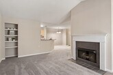 This single-story, one-bedroom, one-bathroom unit offers a practical and comfortable layout across a well-utilized floor plan. The living room serves as a standout space, featuring dramatic vaulted ceilings that lend a sense of openness well beyond the room's footprint, along with a tile-surround wood-burning fireplace with a classic white mantel. Carpet flooring extends throughout the living areas and bedroom, contributing to a warm, quiet ambiance.

The dining area connects seamlessly to the living room and is highlighted by a pendant chandelier. The galley-style kitchen is equipped with light wood cabinetry, laminate countertops, wood-look flooring, and white appliances including a refrigerator, range, and dishwasher. A dedicated entry hallway provides a clean transition into the main living space.

The bedroom is generously sized, featuring vaulted ceilings, a sliding glass door leading to a private outdoor balcony, and direct access to both a spacious walk-in closet with wire shelving and the full bathroom. The bathroom includes an extended vanity with a single sink, light wood cabinetry, wood-look flooring, and a tub-shower combination.