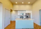 Located at 4770 West Ln in Stockton, CA, this single-floor, 2-bedroom, 2-bathroom residence offers a well-designed layout with modern finishes throughout. The open-concept kitchen serves as the heart of the home, anchored by a central island with a double stainless steel sink and light countertops. White cabinetry reaches toward the high ceilings, complemented by a full suite of stainless steel appliances including a side-by-side refrigerator with ice and water dispenser, an electric range, and an over-the-range microwave. A built-in dishwasher adds to the kitchen's functionality. Warm hardwood-style flooring flows through the main living areas, while recessed lighting illuminates the space. Windows allow natural light to filter in, offering views of the surrounding neighborhood. The bedrooms are carpeted for comfort, each featuring sliding panel closets that provide ample storage. The primary bedroom offers a well-proportioned layout with convenient access to the rest of the unit. The bathrooms include a clean, tiled tub-shower combination with brushed nickel fixtures. Overall, the space presents a bright, contemporary aesthetic with a practical and efficient floor plan.