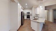 This single-floor residence at 2501 Chester Wood Dr in Raleigh, NC offers a clean, contemporary design throughout. The kitchen serves as a central highlight, featuring white shaker-style cabinetry, light granite countertops, and a full suite of stainless steel appliances including a refrigerator, range, and microwave. A peninsula island with an integrated sink and pendant lighting above adds both functionality and visual interest, while wood-look plank flooring runs seamlessly throughout the space.

The living area is generously proportioned, with recessed lighting, neutral walls, and a ceiling fan contributing to a bright, open atmosphere. Bedrooms are well-sized, each benefiting from the consistent wood-look flooring and natural light through framed windows with outdoor views. At least one bedroom includes access to a spacious walk-in closet outfitted with full wire shelving systems for organized storage.

The bathrooms are thoughtfully finished, with one featuring a wide vanity with white cabinetry, a large mirror, and bright lighting. A separate tub-shower combination with tiled surround and chrome fixtures is also present. The overall ambiance is modern, clean, and move-in ready.