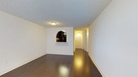 This single-floor residential unit offers a clean, functional layout with a cohesive design throughout. The living area is a standout feature, showcasing rich dark hardwood flooring, crisp white walls, and a textured ceiling. A distinctive arched pass-through window connects the living space to the kitchen, adding a classic architectural touch while maintaining an open feel. Natural light enters through a large window equipped with a wall-mounted HVAC unit, keeping the space comfortable year-round.

The kitchen is thoughtfully updated with dark espresso cabinetry, white countertops, a glass tile backsplash, and stainless steel appliances including a refrigerator and dishwasher. A tall pantry cabinet and under-cabinet lighting add both storage and practicality to the galley-style layout.

The bedrooms feature neutral carpet flooring, textured ceilings, and bright windows with wall HVAC units. Generous closet space with built-in shelving is provided in at least one bedroom, offering ample storage solutions.

The bathroom is finished with white tile surrounding a full soaking tub and shower combination, complete with chrome fixtures and a curved curtain rod. The overall palette of the unit is light and neutral, creating a clean, move-in ready atmosphere throughout.