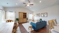 This single-story home features a thoughtfully designed open-concept layout connecting the living room, dining area, and kitchen into one cohesive, light-filled space. The living room is a standout, boasting vaulted ceilings with a ceiling fan, recessed lighting, and rich hardwood flooring. Large windows dressed with sheer white curtains invite abundant natural light, creating a warm and airy atmosphere.

The kitchen is equipped with white shaker cabinetry, stainless steel appliances, granite countertops, and a peninsula with bar seating and pendant lighting overhead. The adjacent dining area comfortably accommodates a full table and benefits from the same high ceilings that amplify the sense of space.

The primary bedroom features a ceiling fan, a window with outdoor views, and neutral tones for a calm, restful environment. Additional bedrooms are similarly bright, each with windows providing natural light. The bathrooms are finished with white vanity cabinetry and granite countertops. A dedicated laundry room with full-size washer and dryer adds everyday convenience. Two closets and a hallway complete the functional layout of this well-appointed home.