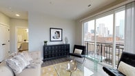 Located in the heart of downtown Columbus, Ohio, this single-floor residence at 223 E Town St offers a sleek, contemporary living experience with direct access to the city's vibrant urban core. The living area is thoughtfully designed with a clean, modern aesthetic, showcasing smooth neutral-toned walls, hardwood-style flooring, and large floor-to-ceiling sliding glass doors that flood the space with abundant natural light. These expansive windows open to a private balcony, framing impressive views of the Columbus skyline — a standout feature that brings the energy of the city directly into the living space. The interior is well-proportioned, offering a comfortable and open feel suited for both relaxing and entertaining. Ceiling-mounted ventilation and recessed fixtures contribute to the streamlined, uncluttered look throughout. The overall ambiance is polished and urban, combining functional design with upscale finishes. Positioned in a prime downtown location, this space provides convenient proximity to Columbus's restaurants, cultural institutions, and business districts, making it an ideal setting for those who value modern city living.