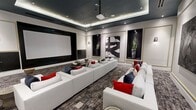 This elegant private screening room delivers a premium cinematic experience wrapped in refined, contemporary design. The space is anchored by a large projection screen mounted on a dark-framed accent wall, paired with a ceiling-mounted projector suspended from a dramatic tray ceiling finished in deep charcoal and outlined with soft ambient LED lighting. Recessed spotlights complement the layered illumination, creating a warm yet moody atmosphere ideal for entertainment.

The room is furnished with multiple oversized white sectional sofas arranged in a theater-style layout, all dressed with bold red and navy accent pillows that introduce rich contrast against the neutral palette. A sleek oval dark coffee table serves as a central focal point between seating arrangements. Underfoot, a textured gray area rug grounds the room and adds depth to the overall design.

The walls are adorned with a curated selection of large-scale abstract black-and-white artworks, each framed within gold-trimmed recessed wall niches that also showcase tall potted plants, lending a polished gallery-like character to the space. Wall sconces provide additional accent lighting throughout.

Together, the architectural details, premium furnishings, and thoughtful art integration make this screening room a standout example of modern luxury design.