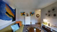 This 1-bedroom, 1-bathroom single-floor residence offers a thoughtfully arranged layout that makes excellent use of its space. The living area serves as the heart of the home, featuring durable wood-style flooring that adds warmth and a modern touch underfoot. A textured ceiling adds a classic architectural detail, while neutral-toned walls provide a versatile backdrop for a variety of décor styles. The living room is bright and welcoming, with ample room for comfortable seating and a dedicated area for a coffee table and accent furnishings. Colorful wall art and decorative accents bring personality and vibrancy to the space. A hallway connects the living area to the private bedroom and bathroom, offering a natural separation between living and sleeping spaces. The layout flows smoothly from one area to the next, contributing to an efficient and functional floor plan. Overall, this residence strikes a balance between practicality and comfort, making it an ideal space for those seeking a cozy yet stylish single-floor home with well-appointed interiors and a welcoming ambiance throughout.