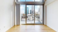 Located in the Vue building in the heart of uptown Charlotte, NC, this two-floor loft-style residence offers a thoughtfully designed open layout spread across two levels. The main floor features light-toned hardwood flooring throughout, lending warmth to the open-concept living and kitchen area. The well-appointed kitchen is equipped with stainless steel appliances, including a full-size range, built-in microwave, and side-by-side refrigerator, complemented by rich dark wood cabinetry, granite countertops, and a double stainless steel sink. Floor-to-ceiling windows and sliding glass doors flood the living area with natural light and open to a private balcony showcasing dramatic views of the Charlotte skyline. The upper level, accessible via an interior staircase with metal railings, features plush carpeting and continues to frame the city views through large-format windows, with exposed ductwork adding an industrial loft character. Track lighting runs along the upper ceiling. The two bathrooms include a well-sized primary bath with tile flooring, a soaking tub, walk-in shower with tile surround, dark wood vanity with granite countertop, and a large mirror. A secondary bath provides additional convenience. This residence combines urban sophistication with functional design in one of Charlotte's most prominent addresses.