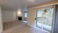 This single-floor, 2-bedroom, 1-bathroom residence offers a well-organized layout designed for comfortable everyday living. The main living area is carpeted and anchored by a classic fireplace with a clean white mantle and tile surround, providing a welcoming focal point. A window alongside the fireplace allows natural light to filter into the space, while neutral-toned walls and light-colored carpet create a bright, understated atmosphere throughout.

A sliding glass door opens directly to a private balcony, offering an appealing transition between indoor and outdoor living. The balcony overlooks a dense, lush tree canopy, providing a serene and natural backdrop that enhances the overall ambiance of the unit.

The layout is efficient and functional, making practical use of the available space across both bedrooms and the shared bathroom. The neutral finishes and soft carpeting contribute to a calm, livable environment. Overall, this residence combines key interior features — including the fireplace and natural light — with appealing outdoor greenery views, making it a comfortable and inviting single-level living space.