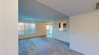 Located in Grandville, Michigan, this single-floor, 2-bedroom, 2-bathroom residence offers a well-organized layout designed for comfortable everyday living. The open-concept living room is generously sized, featuring soft wall-to-wall carpeting, a textured ceiling, and large vertical-blind windows alongside a sliding glass door that fills the space with natural light and provides outdoor access. A pass-through window connects the living area to the kitchen, creating a sense of openness between the two spaces. The galley-style kitchen is equipped with warm wood cabinetry, durable wood-look vinyl plank flooring, stainless steel appliances including a refrigerator, electric range, and microwave, as well as a double sink with ample counter space. The spacious primary bedroom features plush carpeting, a window overlooking the neighborhood, and a textured ceiling. The second bedroom is equally comfortable with soft carpeting and neutral tones throughout. Both bathrooms mirror the kitchen's warm wood cabinetry and vinyl plank flooring; one features a single vanity, while the other offers a full tub-shower combination. A hallway connects the private areas of the home, and a dedicated closet provides additional storage. The overall ambiance is clean, neutral, and move-in ready.