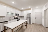 Located at 1521 Lee Rd in Douglasville, GA, this thoughtfully designed one-bedroom, one-bathroom residence offers a clean, modern aesthetic throughout its efficiently laid-out single floor. The open-concept kitchen is a standout feature, showcasing crisp white shaker cabinetry, a classic subway tile backsplash, granite countertops, and a full suite of stainless steel appliances including a refrigerator, electric range, microwave, and dishwasher. A central kitchen island provides additional prep and dining space, while light wood-tone flooring ties the kitchen and living area together seamlessly. Recessed lighting and a ceiling fan keep the living space bright and comfortable, and a glass door leads to a private balcony with views of surrounding greenery. The spacious bedroom features plush carpet flooring, dual windows that invite natural light and outdoor views, and a ceiling fan. An adjacent walk-in closet offers wire shelving on multiple walls for generous storage. The bathroom is finished with a white vanity, granite countertop, a framed marble-style mirror, and wood-tone flooring. A dedicated laundry room with wire shelving and a full-size Whirlpool washer/dryer unit adds everyday convenience to this well-rounded residence.